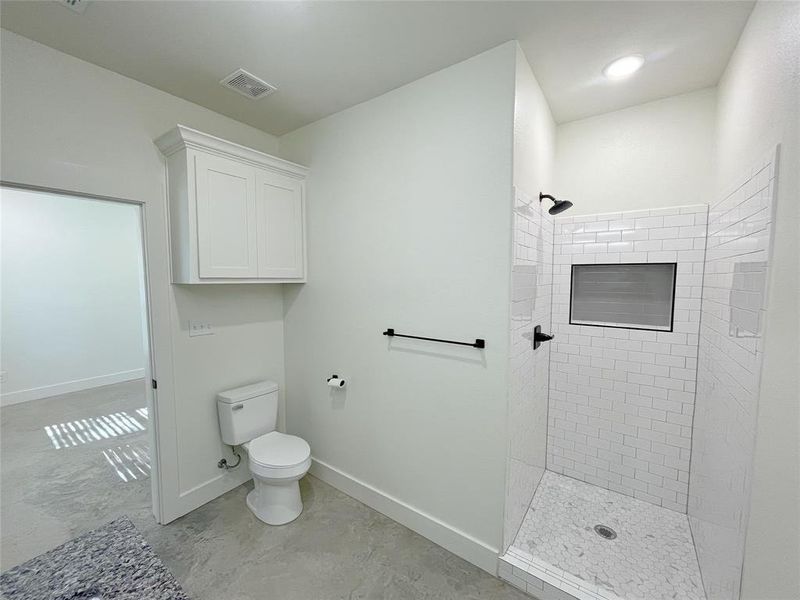 Bathroom featuring tiled shower and toilet