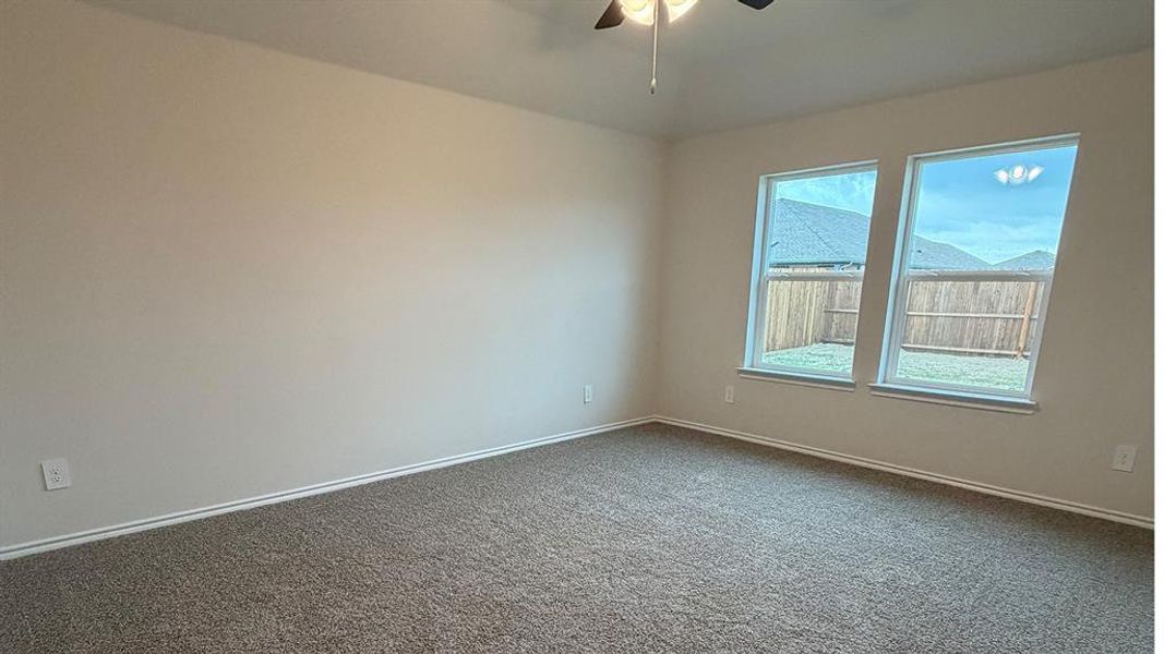 Spare room featuring a ceiling fan and dark colored carpet