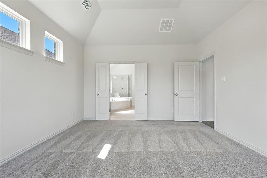 Unfurnished bedroom with light carpet, connected bathroom, and vaulted ceiling Unfurnished bedroom with light carpet, connected bathroom, and vaulted ceiling