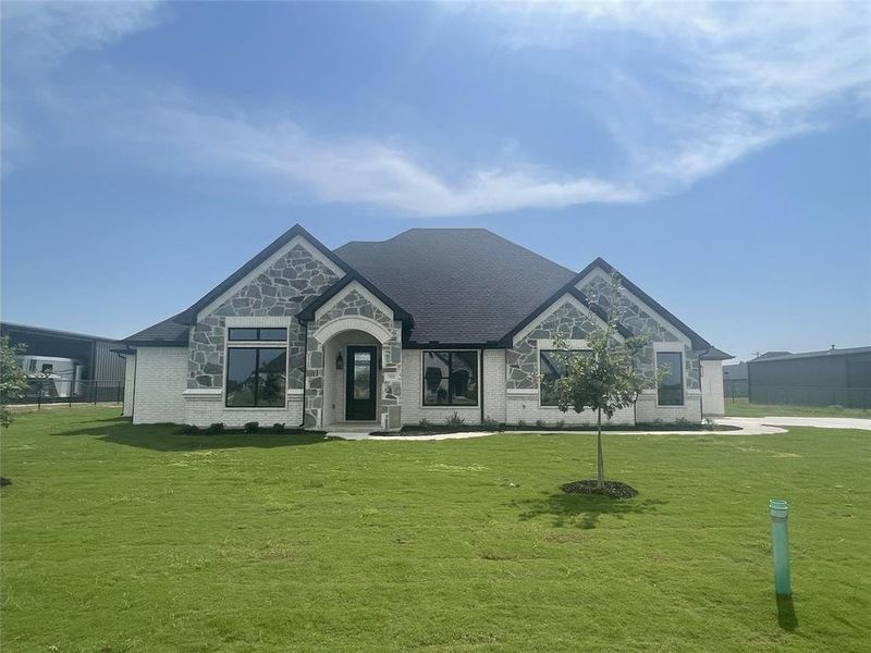 French country inspired facade with a front yard, brick siding, and stone siding