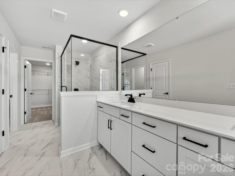 oversized dual vanity with quartz. Countertops. cabinets feature soft close doors & drawers. 12X24 Tiled floor & shower with bench leads to large primary closet