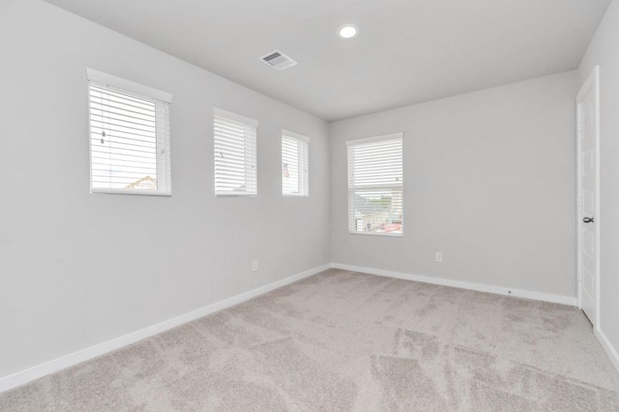 generously sized secondary bedrooms, showcasing 5-panel doors with modern hardware, large windows adorned with privacy blinds, and spacious closets boasting sleek and contemporary finishes. Sample photo of completed home with similar floor plan. Actual colors and selections may vary.
