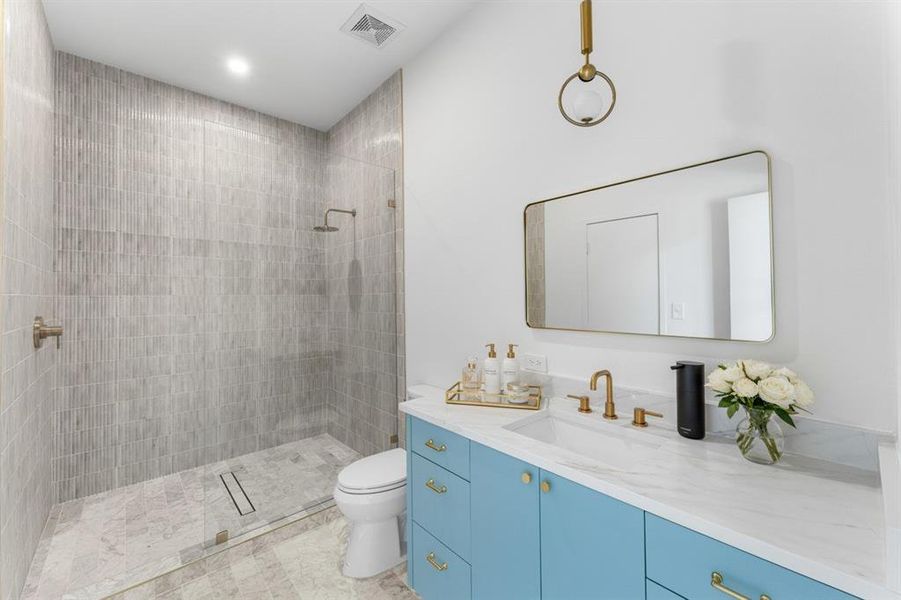 Bathroom with tiled shower, vanity, and recessed lighting