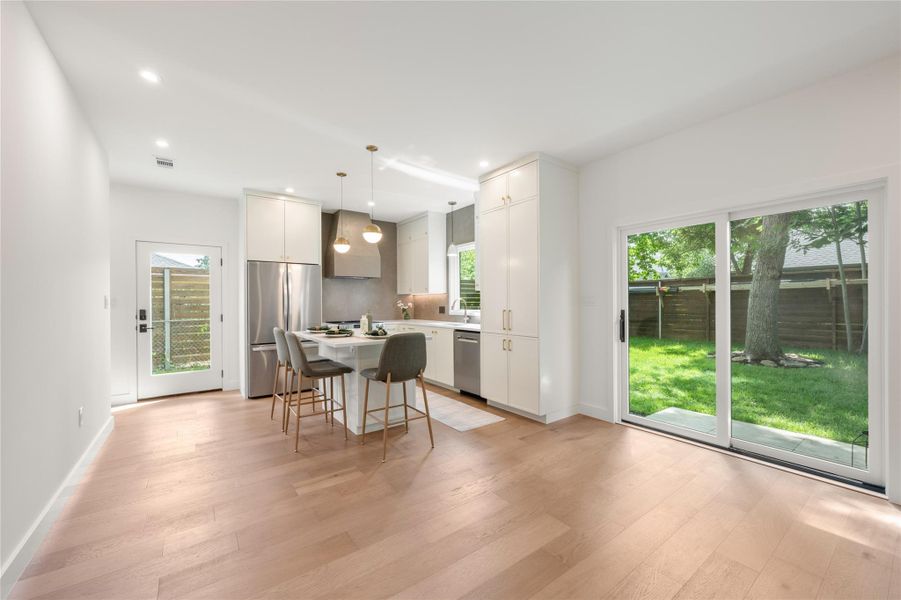 A well-lit kitchen with gleaming wood floors and access to a lush backyard through sliding glass doors. A well-lit kitchen with gleaming wood floors and access to a lush backyard through sliding glass doors.