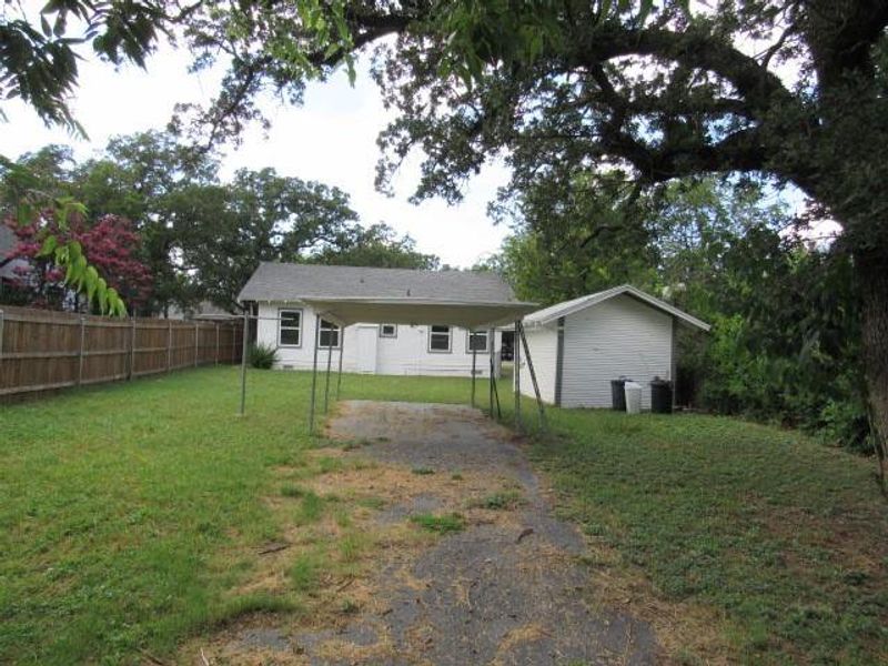Rear view of property featuring driveway and a carport Rear view of property featuring driveway and a carport