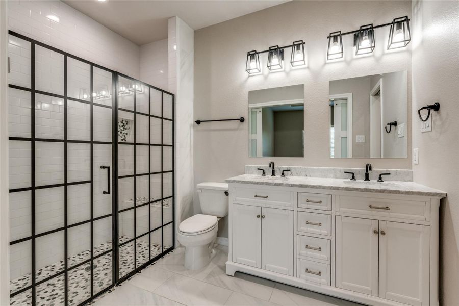 Bathroom featuring double vanity and tiled shower Bathroom featuring double vanity and tiled shower