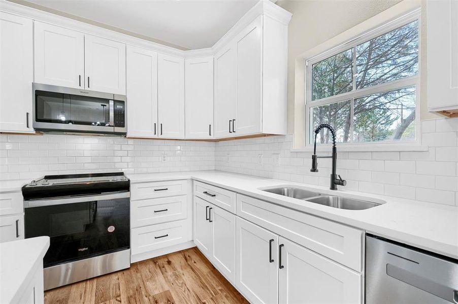 Kitchen featuring stainless steel appliances, white cabinetry, and sink