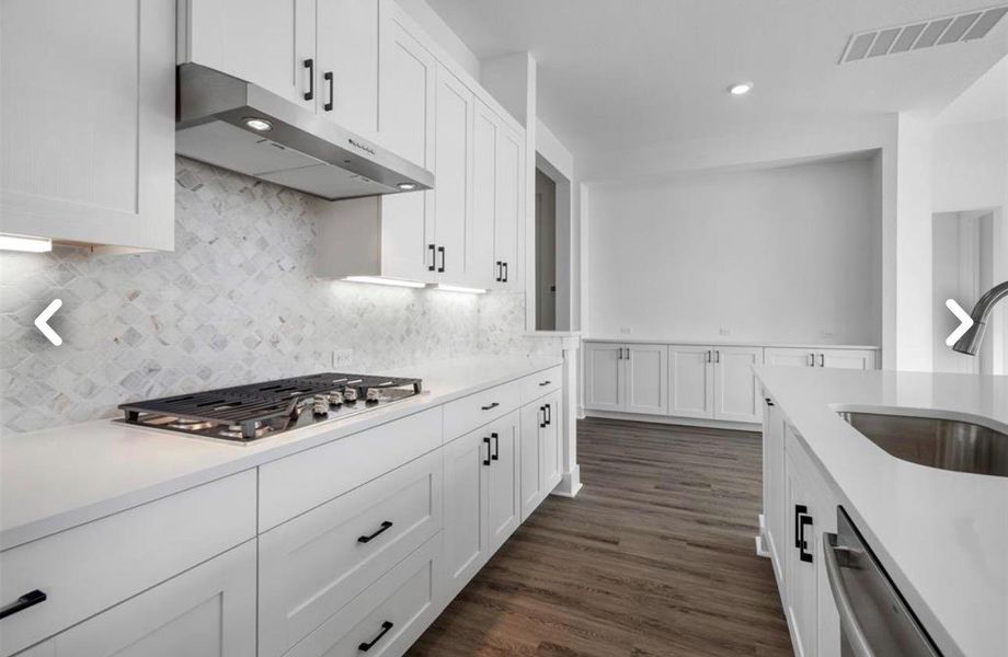 Kitchen with white cabinets, light stone countertops, dark wood finished floors, stainless steel appliances, and recessed lighting
