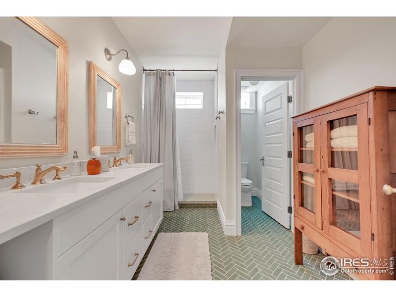 Basement dual sink bathroom with gorgeous herringbone tile floors