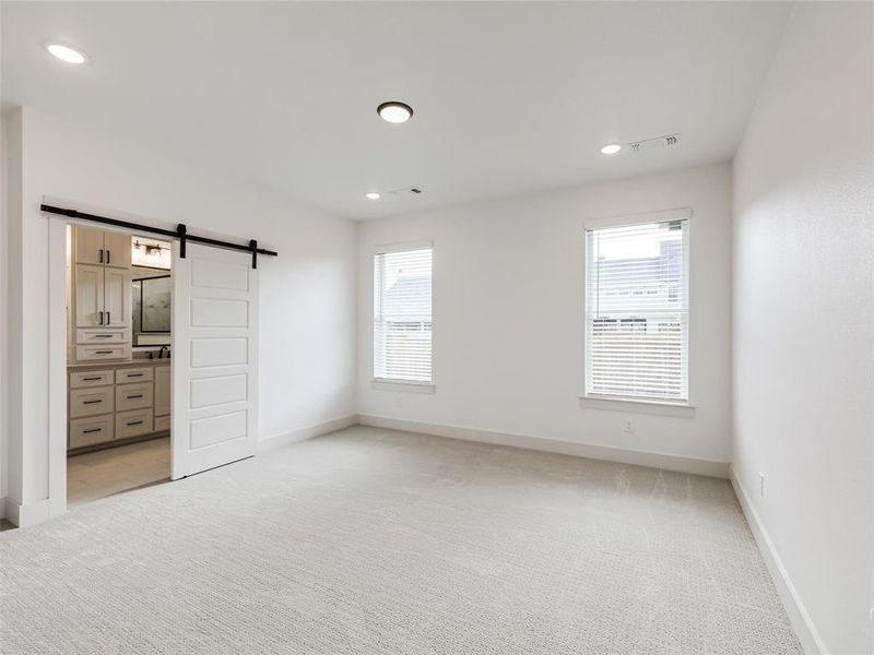 Primary bedroom with ensuite bathroom with barn door and large walk-in closet. Primary bedroom with ensuite bathroom with barn door and large walk-in closet.