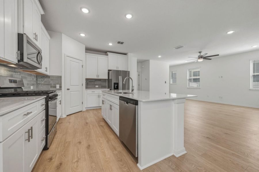 Kitchen featuring stainless steel appliances, tasteful backsplash, white cabinets, a kitchen island with sink, and recessed lighting
