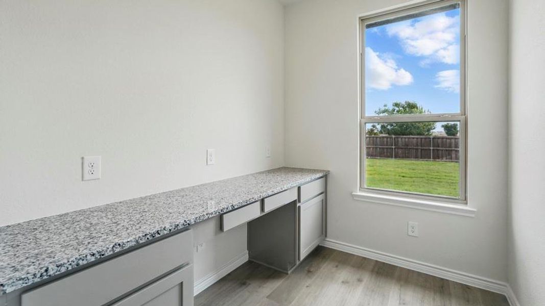 Built-in desk featuring a stone-finish countertop and light grey cabinetry Built-in desk featuring a stone-finish countertop and light grey cabinetry