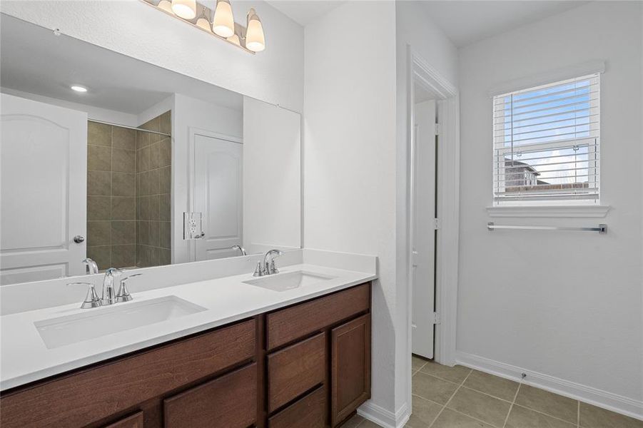 This primary bathroom is definitely move-in ready! Featuring stained cabinets with light countertops, dual vanities, high ceilings, custom paint, sleek and dark modern finishes.