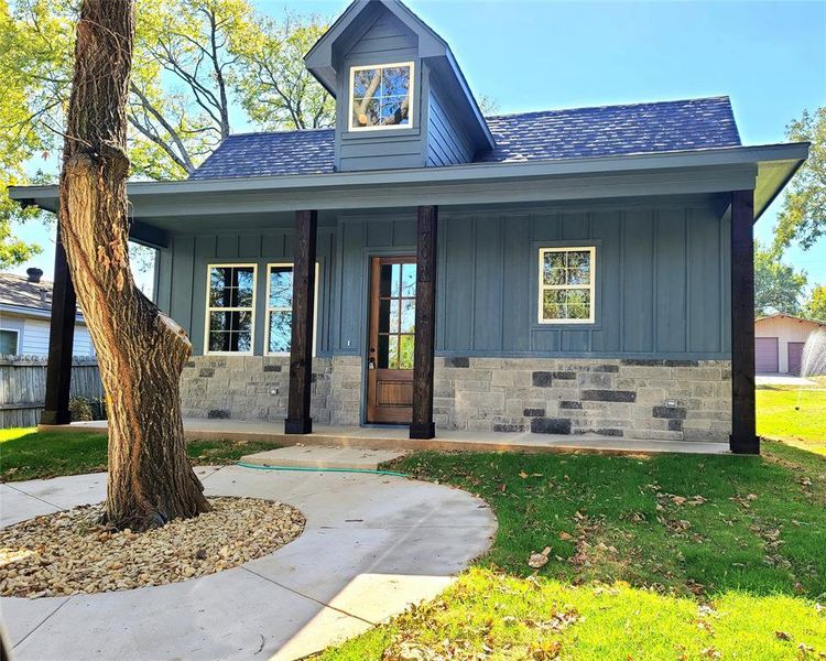 View of front of house featuring covered porch, a front yard, and a garage