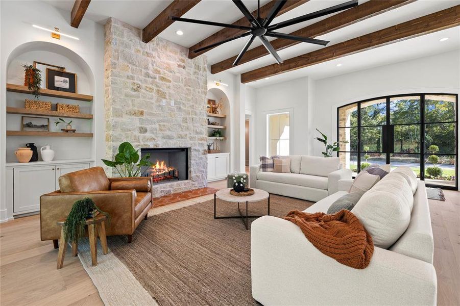 Living area with built in features, light wood-style floors, a stone fireplace, beamed ceiling, and recessed lighting