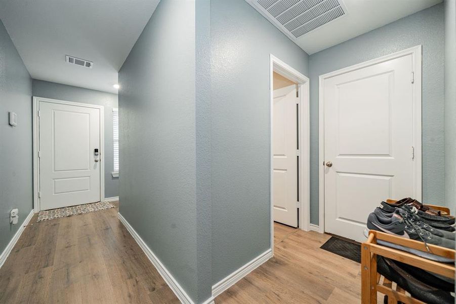 Corridor featuring light wood-style flooring and a textured wall Corridor featuring light wood-style flooring and a textured wall