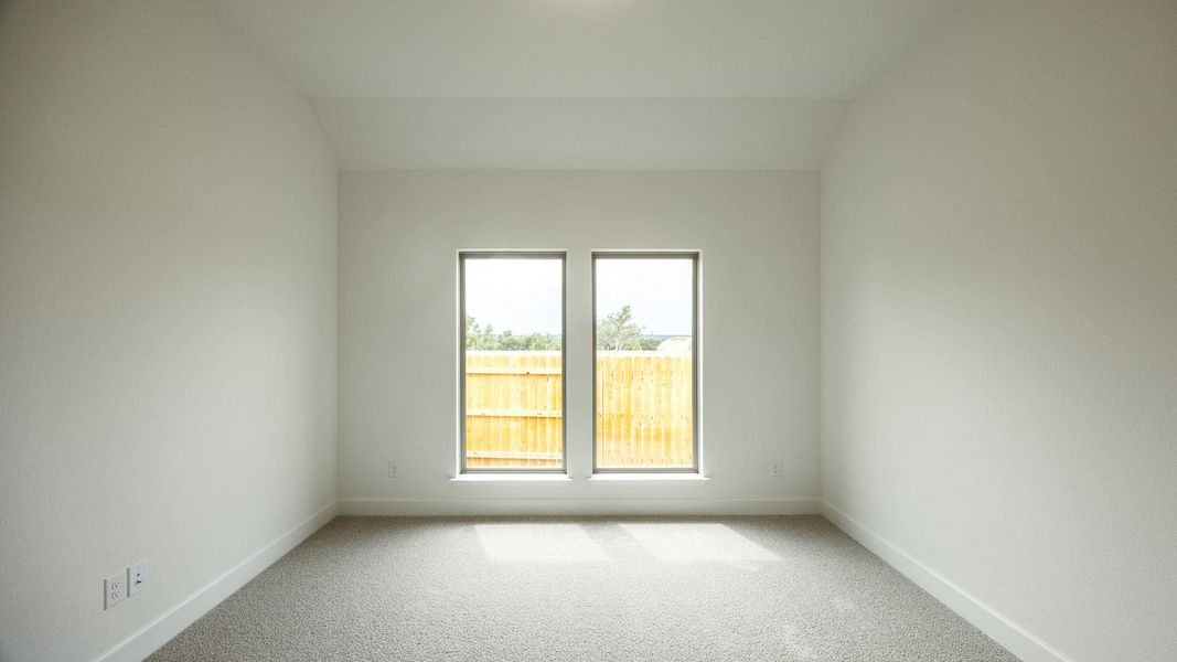 Carpeted empty room featuring vaulted ceiling
