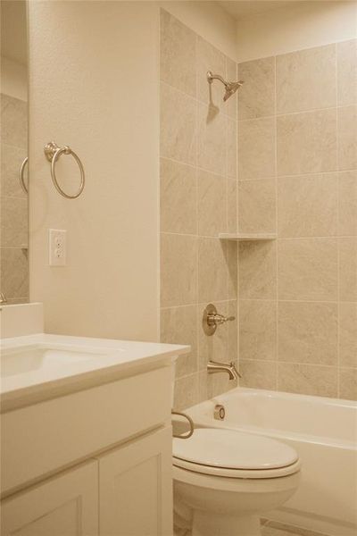 Full bathroom featuring tiled shower / bath, vanity, and toilet