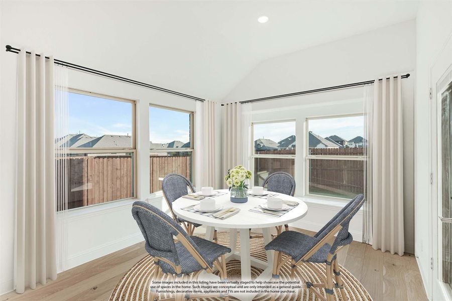 Bright dining area with round white table, four blue chairs, hardwood floors, and large windows with neighborhood views