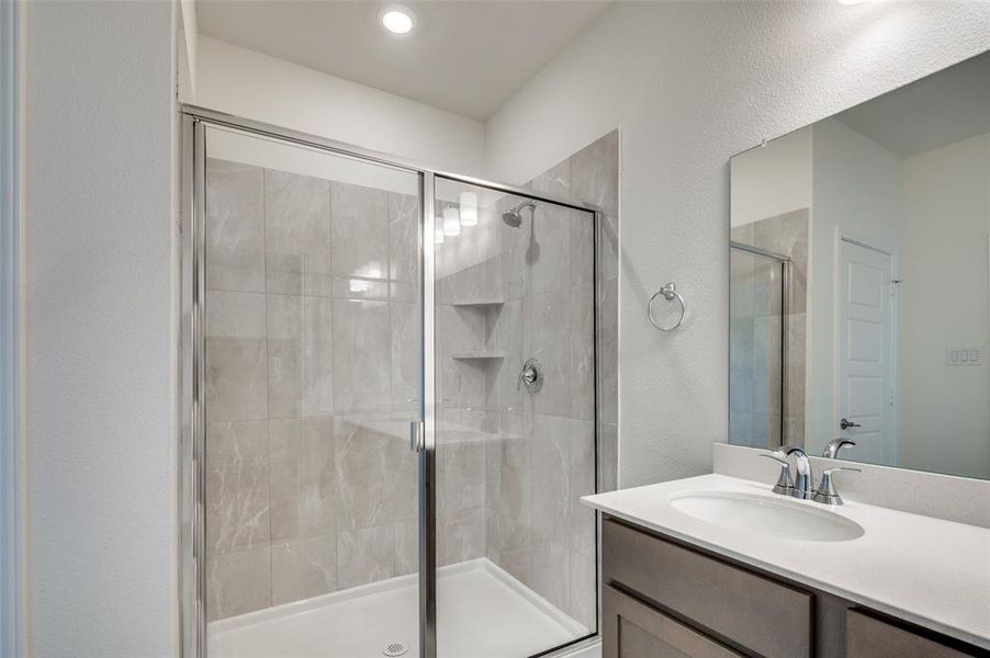 Bathroom featuring a textured wall, a stall shower, and vanity Bathroom featuring a textured wall, a stall shower, and vanity