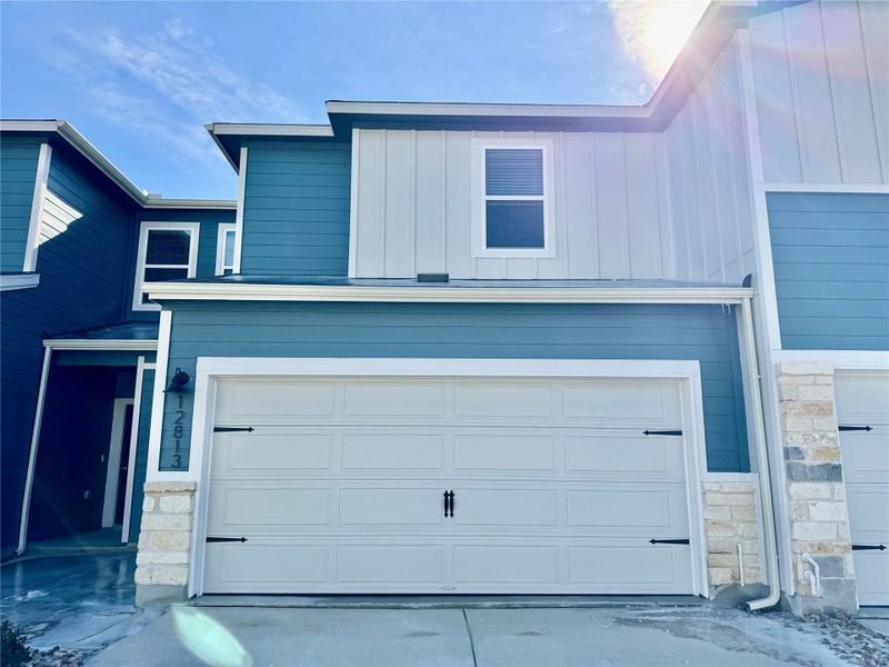 View of front of house with stone siding, a garage, and board and batten siding