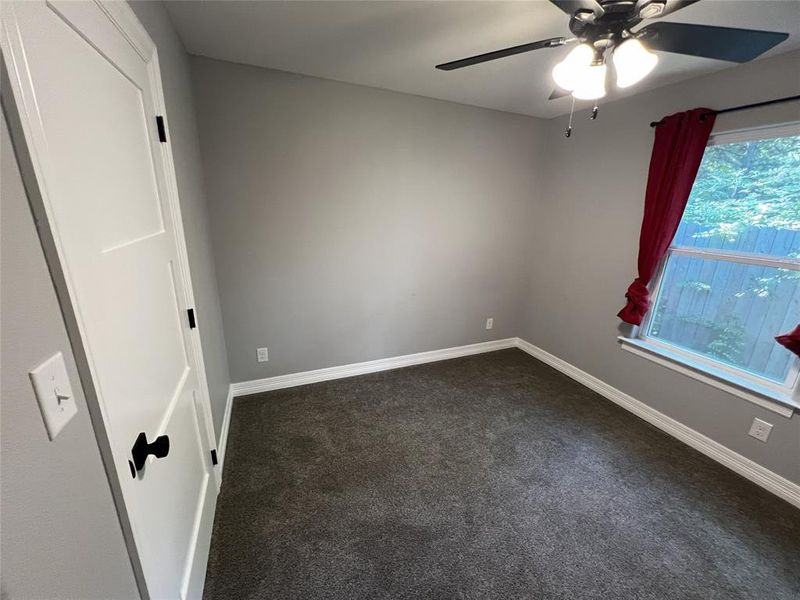Unfurnished room with dark carpet and a ceiling fan Unfurnished room with dark carpet and a ceiling fan