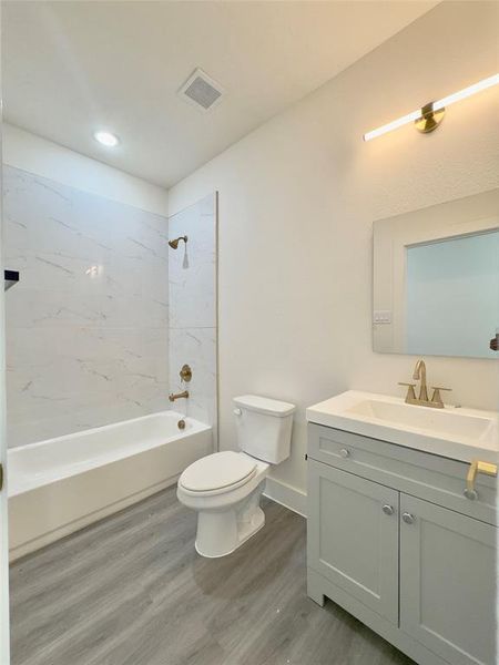 Full bathroom featuring wood-type flooring, tiled shower / bath, vanity, and toilet