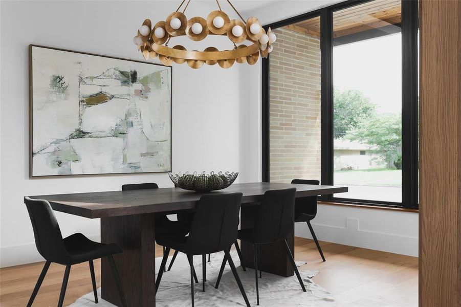 The sophisticated dining room is accented with a recessed white oak planked ceiling and gilded chandelier.