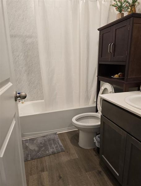 Full bathroom featuring shower / bath combination with curtain, toilet, wood-type flooring, and vanity