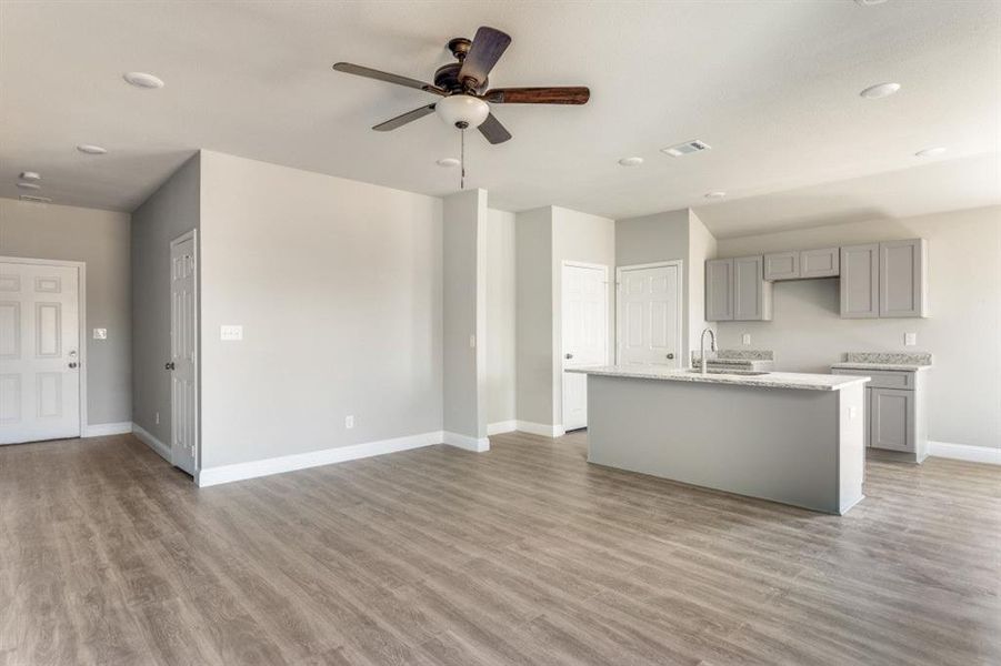 Kitchen featuring gray cabinets, a kitchen island with sink, light wood-type flooring, a ceiling fan, and recessed lighting