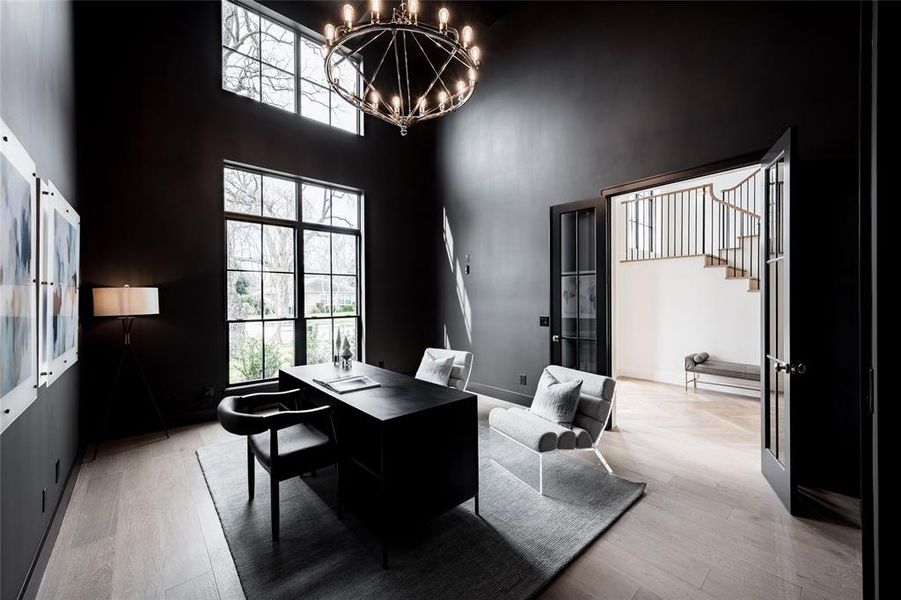 This photo showcases a modern two-story home with a light brick exterior, large windows, and a dark shingled roof. The house features a spacious two-car garage with wooden doors and a welcoming arched entryway. The front lawn is neatly landscaped, enhancing the property's curb appeal.