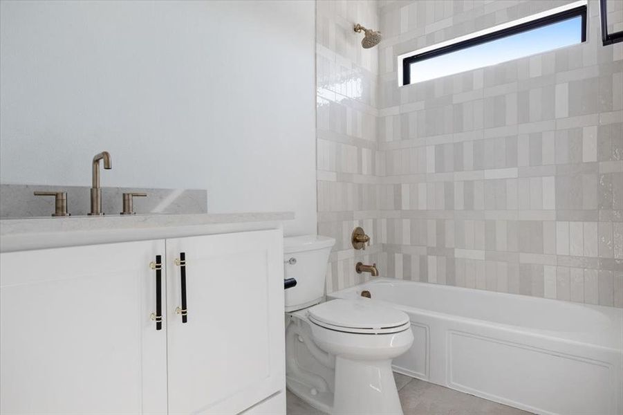 Full bathroom with tile floors, tiled shower / bath, toilet, and vanity