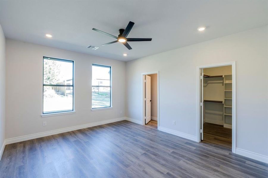 Master bedroom with dark hardwood / wood-style flooring, a closet, ceiling fan, and a spacious closet