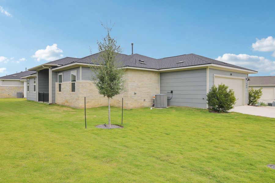 Back of house with a yard, a garage, concrete driveway, and roof with shingles