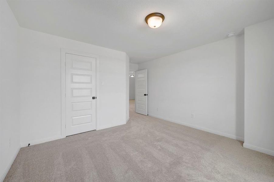 Carpeted room featuring light gray walls, a white five-panel interior door with black hardware, and a semi-flush mount ceiling light fixture