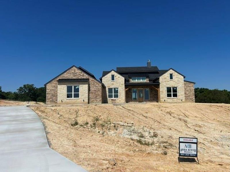 Stone and brick exterior with dark gray shingle roofing and white frame windows