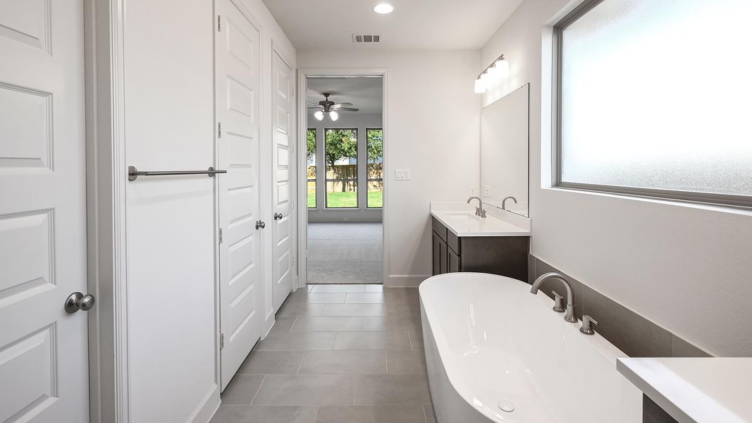 Bathroom featuring vanity, a soaking tub, dark tile patterned flooring, ceiling fan, and recessed lighting Bathroom featuring vanity, a soaking tub, dark tile patterned flooring, ceiling fan, and recessed lighting