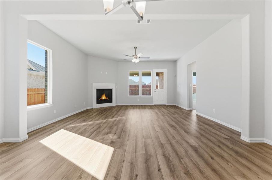 Unfurnished living room featuring a warm lit fireplace, healthy amount of natural light, and light wood-style floors