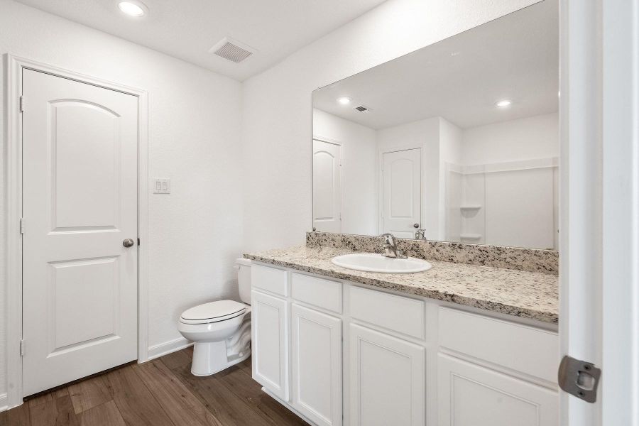 A well-lit bathroom features a spacious vanity with a full-width mirror and modern fixtures.