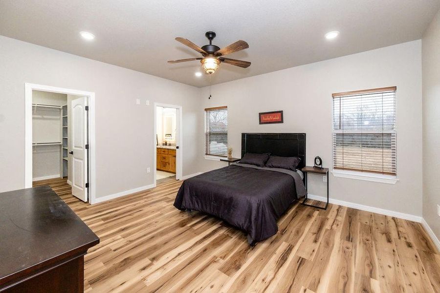 Bedroom with light hardwood / wood-style flooring, ceiling fan, ensuite bathroom, a walk in closet, and a closet