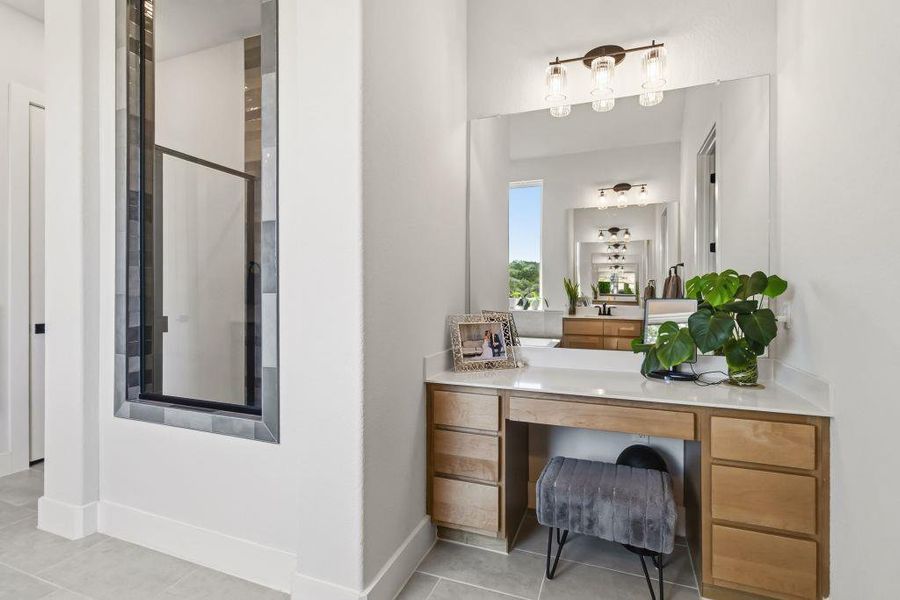 A well-lit vanity area boasts ample counter space and integrated storage, reflecting a view of distant greenery.