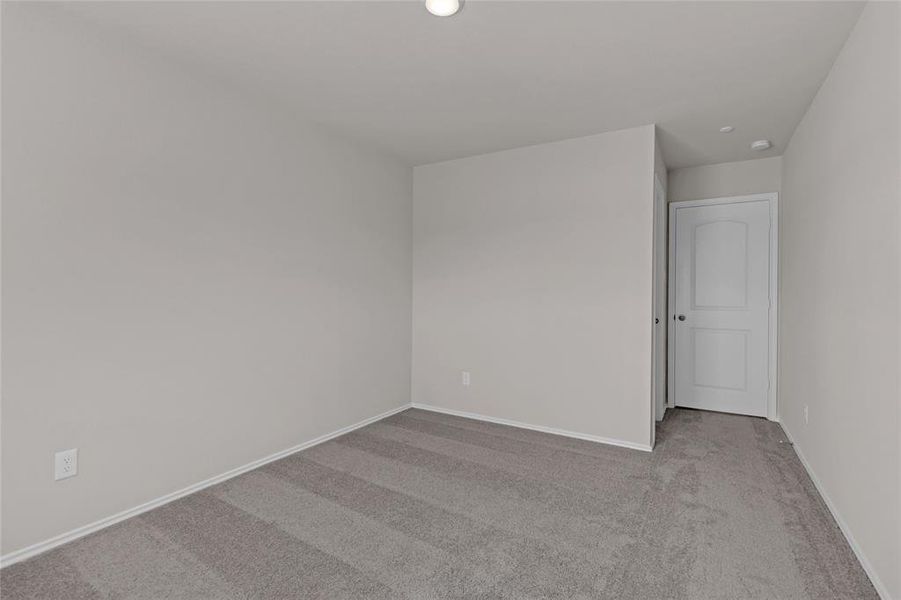 This is a spacious 2nd bedroom angled view with neutral walls and carpet flooring, featuring good natural light.