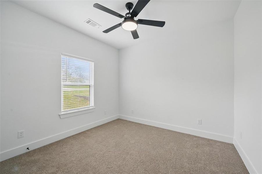 Carpeted spare room with visible vents, baseboards, and a ceiling fan