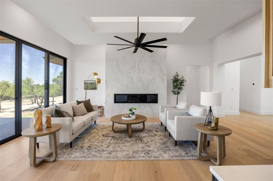 A spacious, naturally illuminated living area showcases a sleek fireplace and broad glass doors opening to verdant outdoor views.