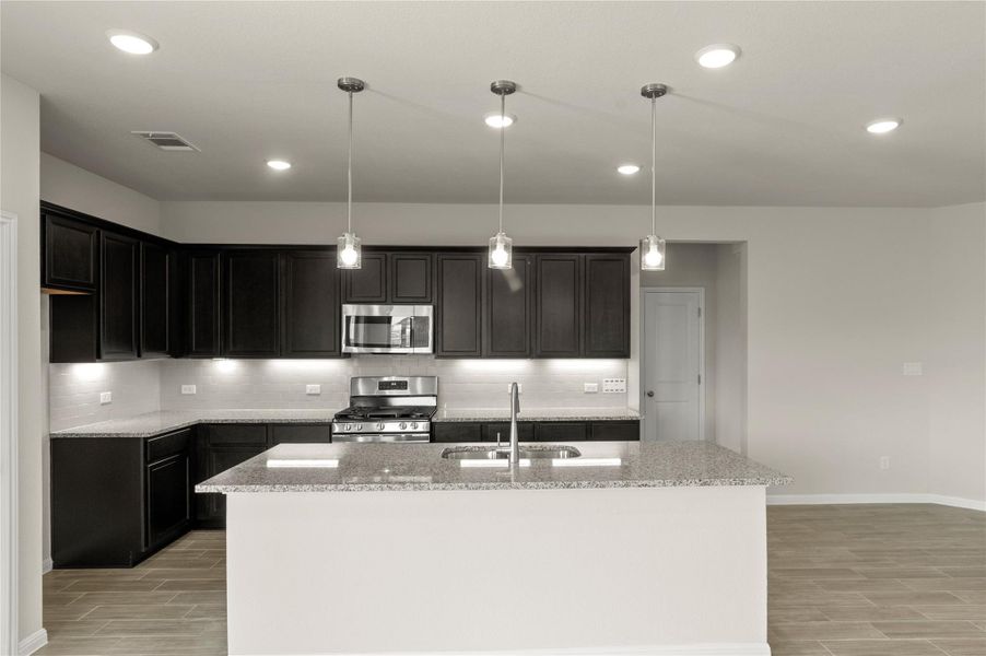 Kitchen with stainless steel appliances, wood tiled floors, light stone countertops, and recessed lighting