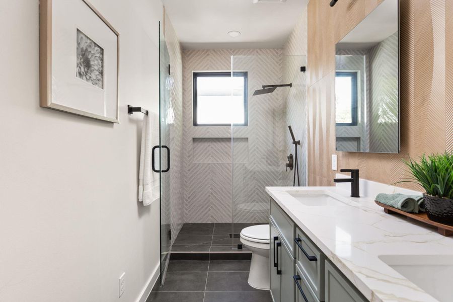 A well-lit bathroom featuring a spacious walk-in shower with sleek glass doors and a modern double vanity.