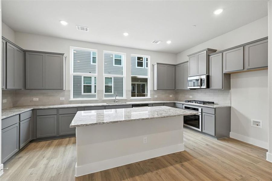 Kitchen featuring gray cabinetry, tasteful backsplash, a center island, and recessed lighting
