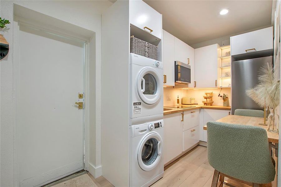 Laundry room featuring stacked washing machine and dryer, light wood finished floors, and recessed lighting Laundry room featuring stacked washing machine and dryer, light wood finished floors, and recessed lighting