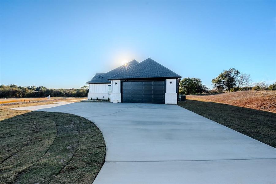 View of side of property with brick siding, driveway, a yard, and roof with shingles View of side of property with brick siding, driveway, a yard, and roof with shingles