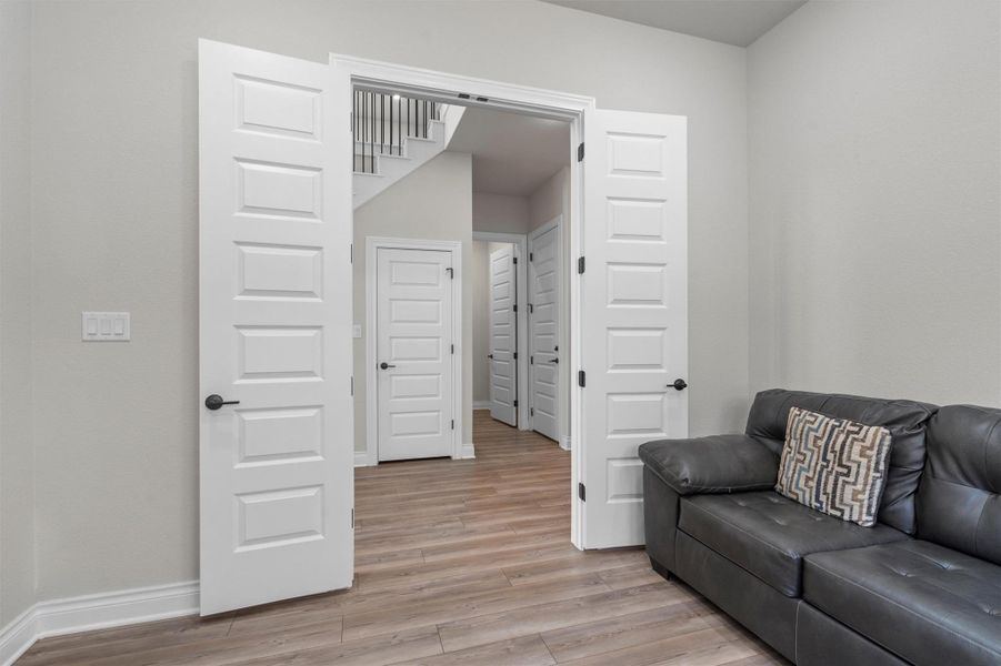 Double doors open to reveal structured hallways and wood-look flooring throughout.